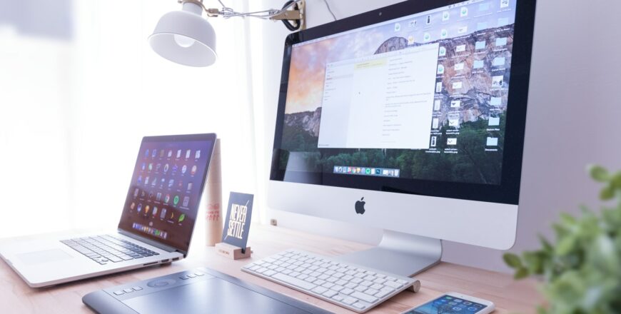 silver iMac near iPhone on brown wooden table