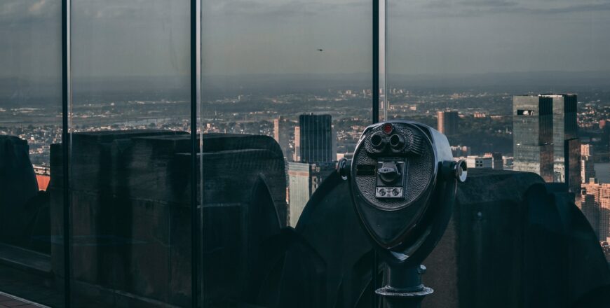 black telescope near glass building during daytime