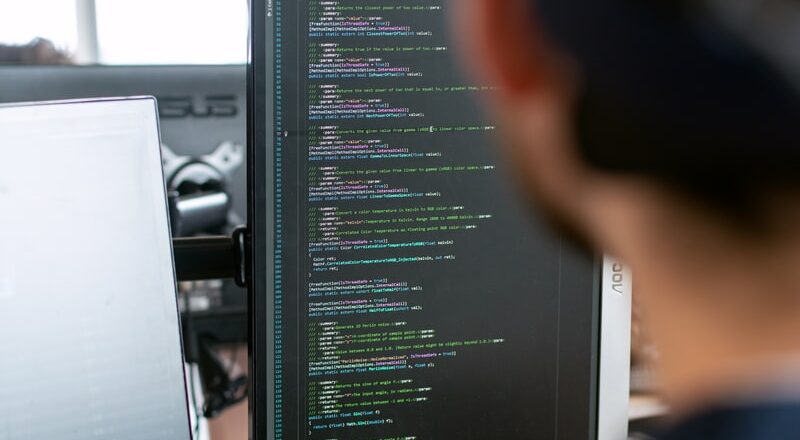 man in black shirt sitting in front of computer monitor