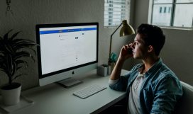man in blue denim jacket facing turned on monitor